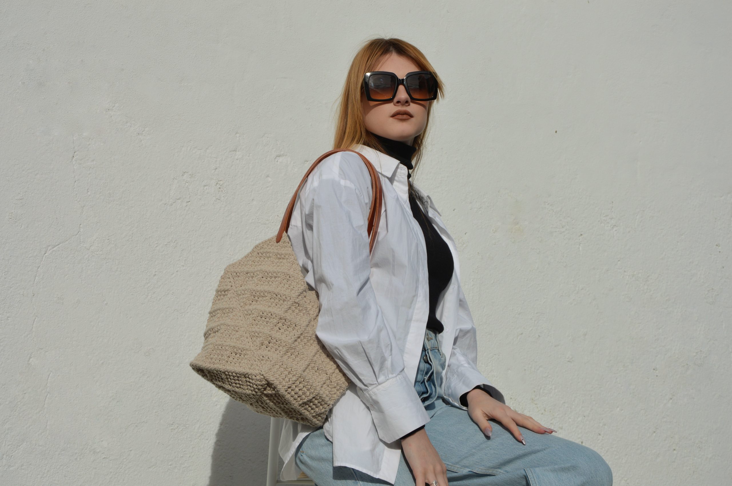 "'Windmill Bag' disponible por €350.00. Esta amplia bolsa artesanal está realizada en macramé con cuerdas de algodón sostenible certificado por OEKO-TEX, con asas de piel de curtido vegetal en color sol. Cada detalle de esta bolsa, desde las técnicas de macramé hasta las asas cosidas a mano con hilos de lino, refleja la artesanía y la calidad de los materiales utilizados."