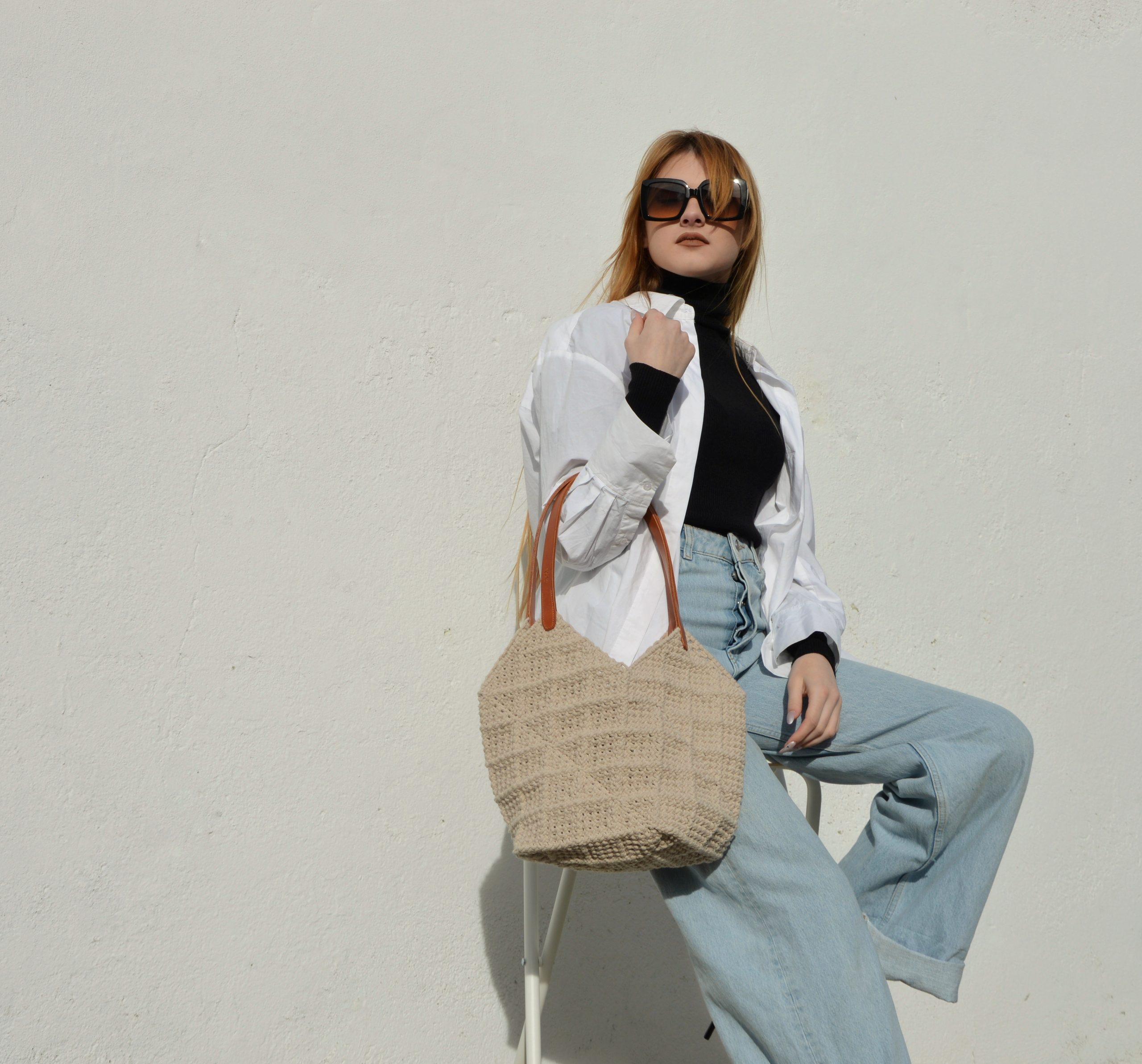 "'Windmill Bag' disponible por €350.00. Esta amplia bolsa artesanal está realizada en macramé con cuerdas de algodón sostenible certificado por OEKO-TEX, con asas de piel de curtido vegetal en color sol. Cada detalle de esta bolsa, desde las técnicas de macramé hasta las asas cosidas a mano con hilos de lino, refleja la artesanía y la calidad de los materiales utilizados."