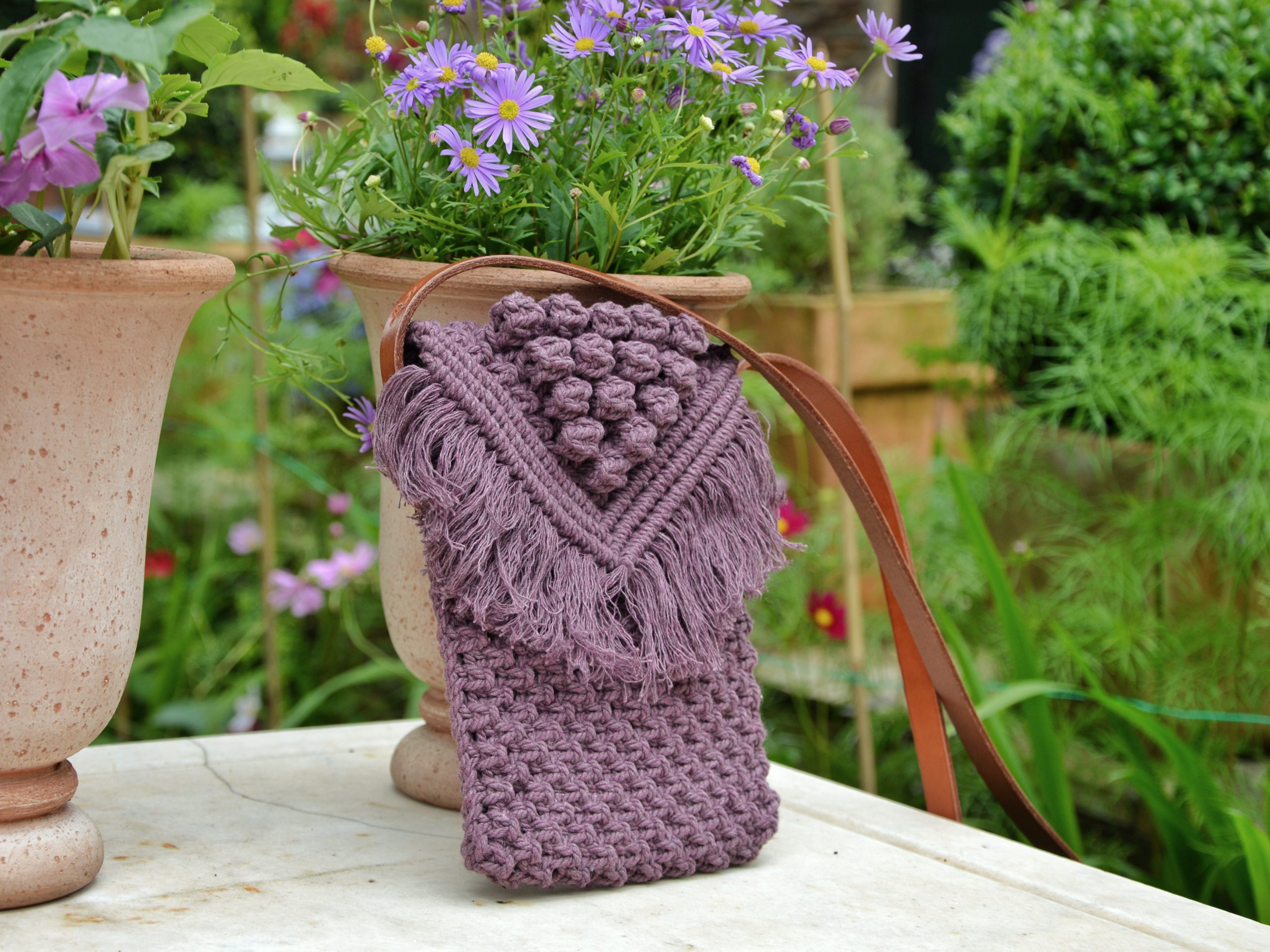 "Cross Body Macramé disponible por €135.00. Esta bolsa cruzada está realizada en macramé con cuerdas de algodón sostenible certificado por OEKO-TEX, con una correa en piel de curtido vegetal. Sus dimensiones aproximadas sin correa son 19cm x 16 cm. Es una pieza artesanal que combina la técnica de macramé con la durabilidad y elegancia de la piel de curtido vegetal."