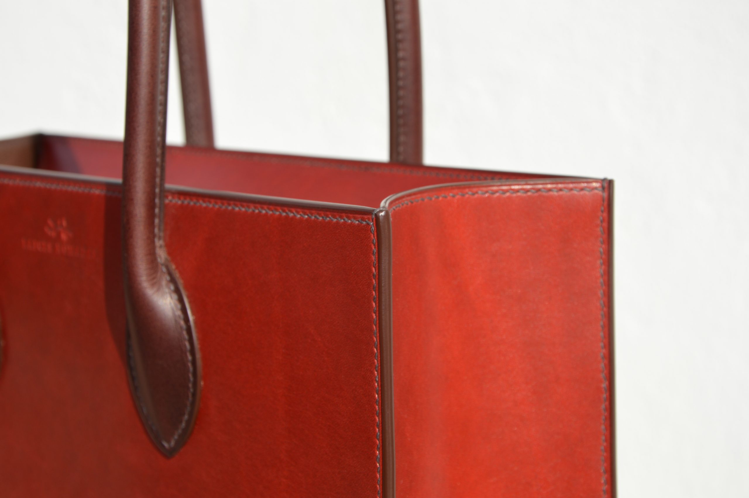 "Tote Bag con cremallera disponible por €1,400.00. Este clásico bolso combina belleza atemporal y líneas armónicas. Creado con el máximo cuidado, está confeccionado con la mejor piel de curtido vegetal española, hilos de lino y cosido completamente a mano. El bolso artesanal presenta un elegante color cereza con asas color tabaco, y está forrado con piel de cabra francesa. Cuenta con un bolsillo interior sin cremallera y otro con cremallera, además de un cierre exterior. Cada detalle de este bolso refleja la artesanía y la calidad de su fabricación, 100% cosido a mano."