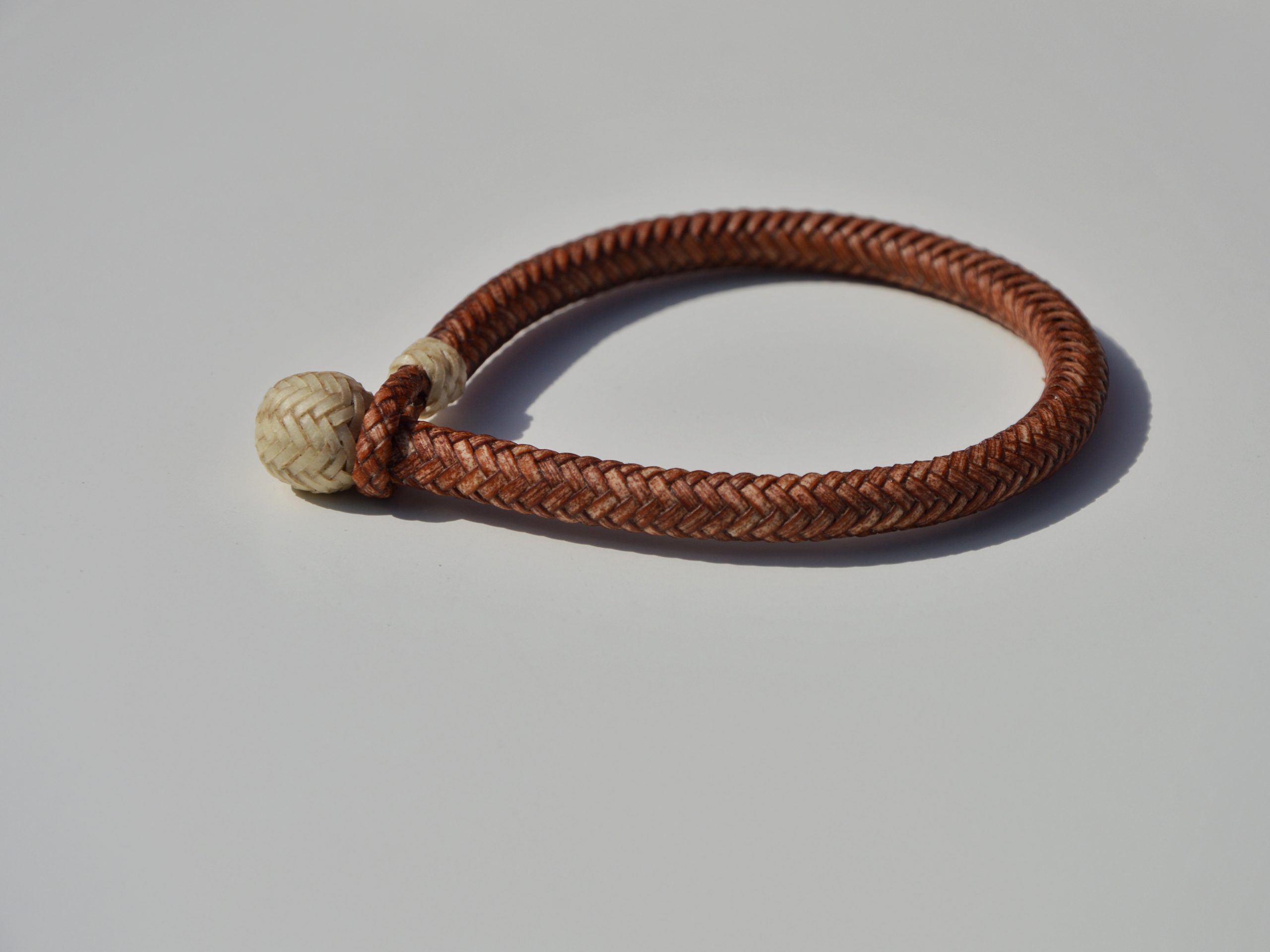 "Pulsera Cuero Crudo disponible por €115.00. Elaborada con técnicas de soguería criolla, esta pulsera está trenzada en cuero crudo con 12 tientos y terminaciones con retejidos. Las coloraciones obtenidas son a base de tintes naturales realizados previamente al trenzado. Es importante tener en cuenta que debido a su trenzado fino y natural, no se recomienda mojarla. Una pulsera que refleja la artesanía y la belleza de los materiales naturales."
