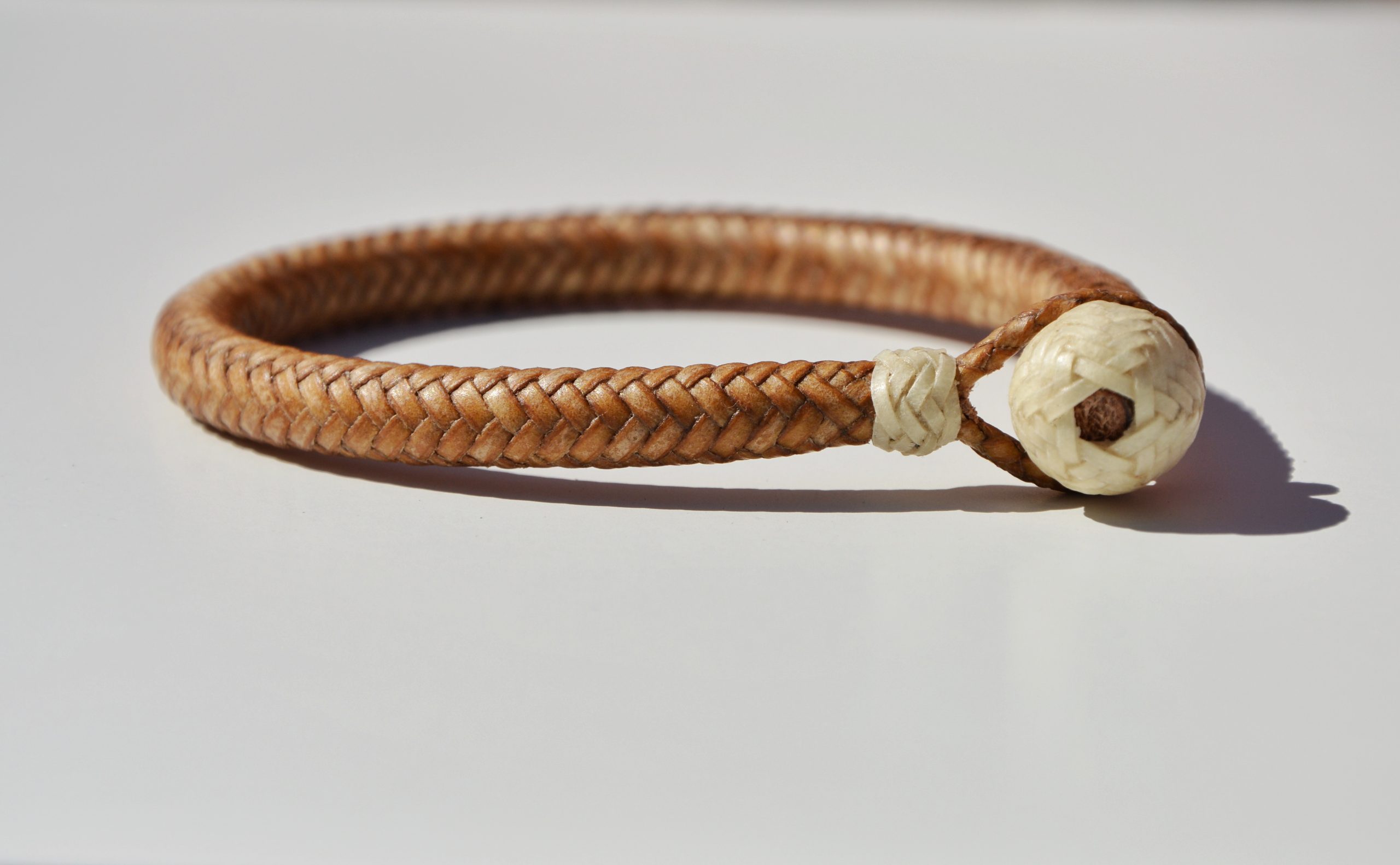 "Pulsera Cuero Crudo disponible por €115.00. Elaborada con técnicas de soguería criolla, esta pulsera está trenzada en cuero crudo con 12 tientos y terminaciones con retejidos. Las coloraciones obtenidas son a base de tintes naturales realizados previamente al trenzado. Es importante tener en cuenta que debido a su trenzado fino y natural, no se recomienda mojarla. Una pulsera que refleja la artesanía y la belleza de los materiales naturales."