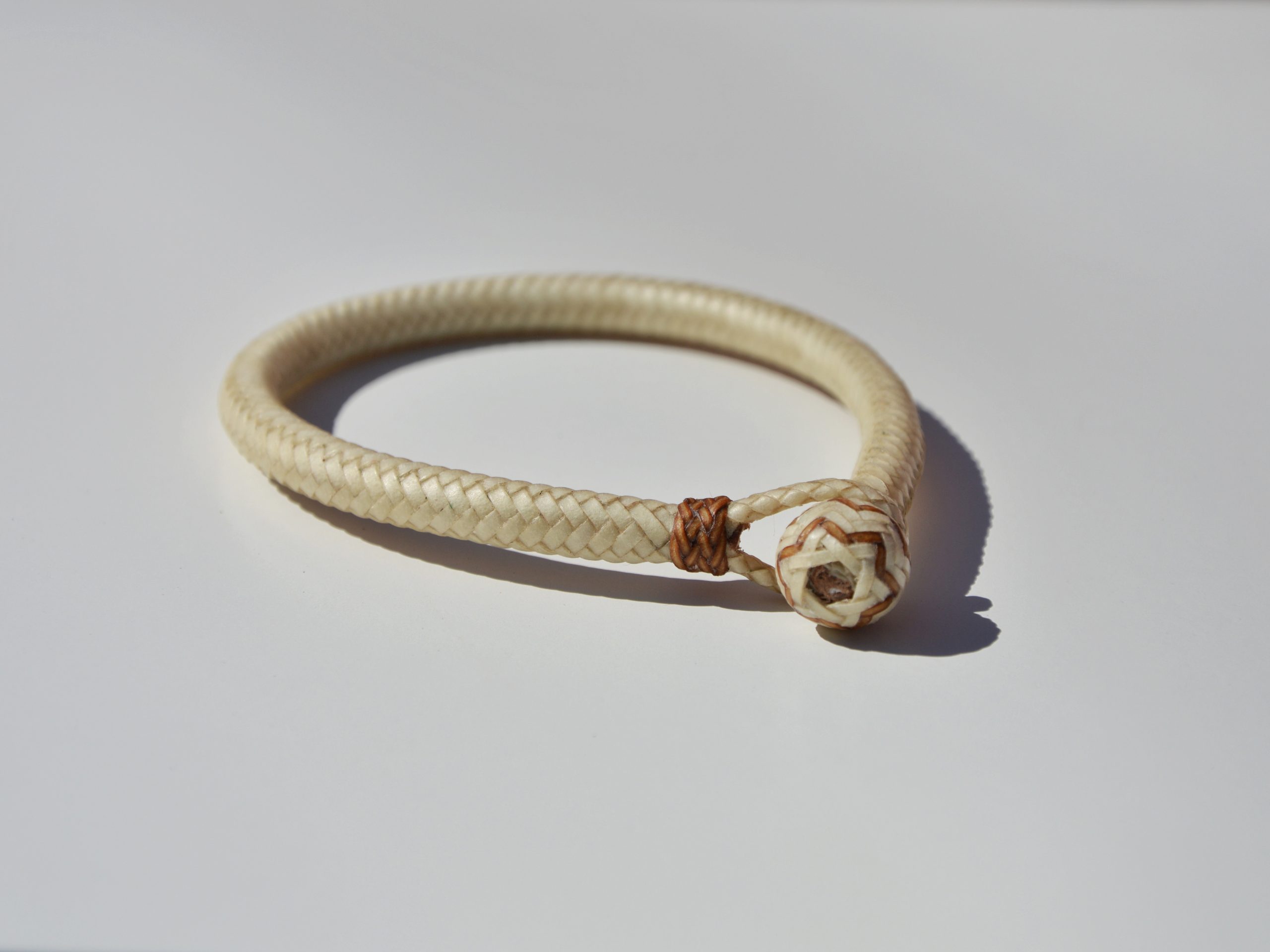 "Pulsera Cuero Crudo disponible por €115.00. Elaborada con técnicas de soguería criolla, esta pulsera está trenzada en cuero crudo con 12 tientos y terminaciones con retejidos. Las coloraciones obtenidas son a base de tintes naturales realizados previamente al trenzado. Es importante tener en cuenta que debido a su trenzado fino y natural, no se recomienda mojarla. Una pulsera que refleja la artesanía y la belleza de los materiales naturales."