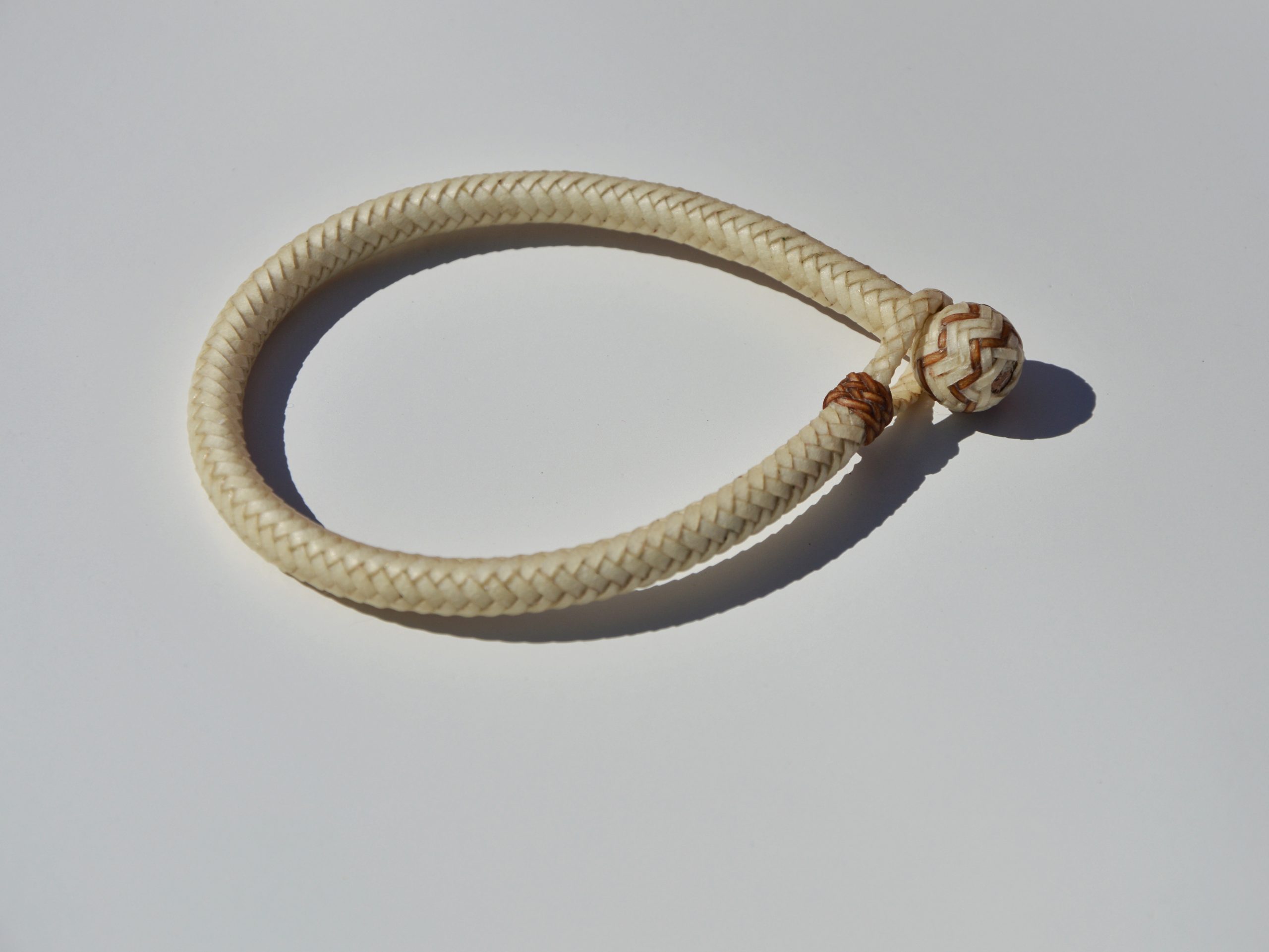 "Pulsera Cuero Crudo disponible por €115.00. Elaborada con técnicas de soguería criolla, esta pulsera está trenzada en cuero crudo con 12 tientos y terminaciones con retejidos. Las coloraciones obtenidas son a base de tintes naturales realizados previamente al trenzado. Es importante tener en cuenta que debido a su trenzado fino y natural, no se recomienda mojarla. Una pulsera que refleja la artesanía y la belleza de los materiales naturales."