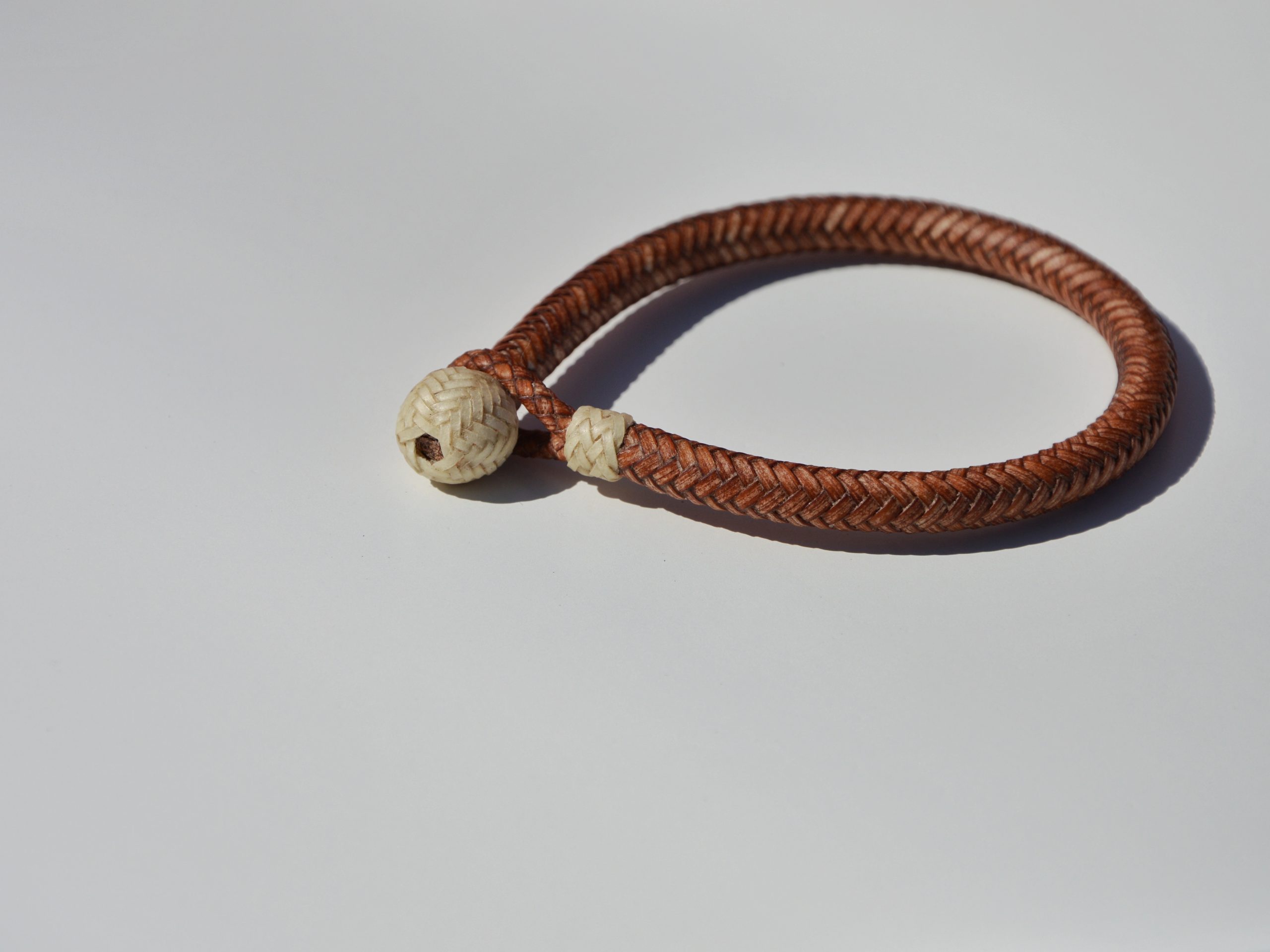 "Pulsera Cuero Crudo disponible por €115.00. Elaborada con técnicas de soguería criolla, esta pulsera está trenzada en cuero crudo con 12 tientos y terminaciones con retejidos. Las coloraciones obtenidas son a base de tintes naturales realizados previamente al trenzado. Es importante tener en cuenta que debido a su trenzado fino y natural, no se recomienda mojarla. Una pulsera que refleja la artesanía y la belleza de los materiales naturales."