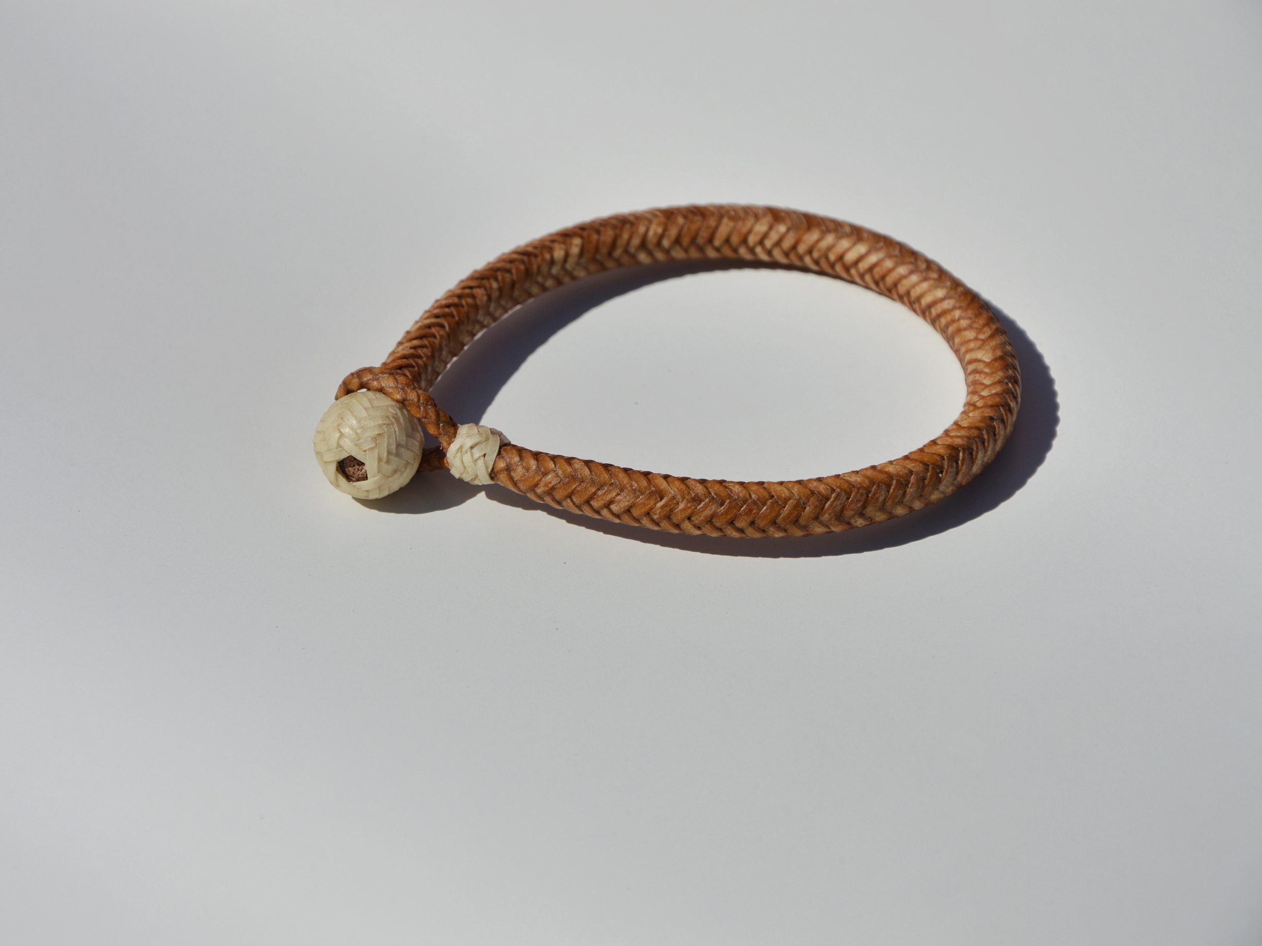 "Pulsera Cuero Crudo disponible por €115.00. Elaborada con técnicas de soguería criolla, esta pulsera está trenzada en cuero crudo con 12 tientos y terminaciones con retejidos. Las coloraciones obtenidas son a base de tintes naturales realizados previamente al trenzado. Es importante tener en cuenta que debido a su trenzado fino y natural, no se recomienda mojarla. Una pulsera que refleja la artesanía y la belleza de los materiales naturales."