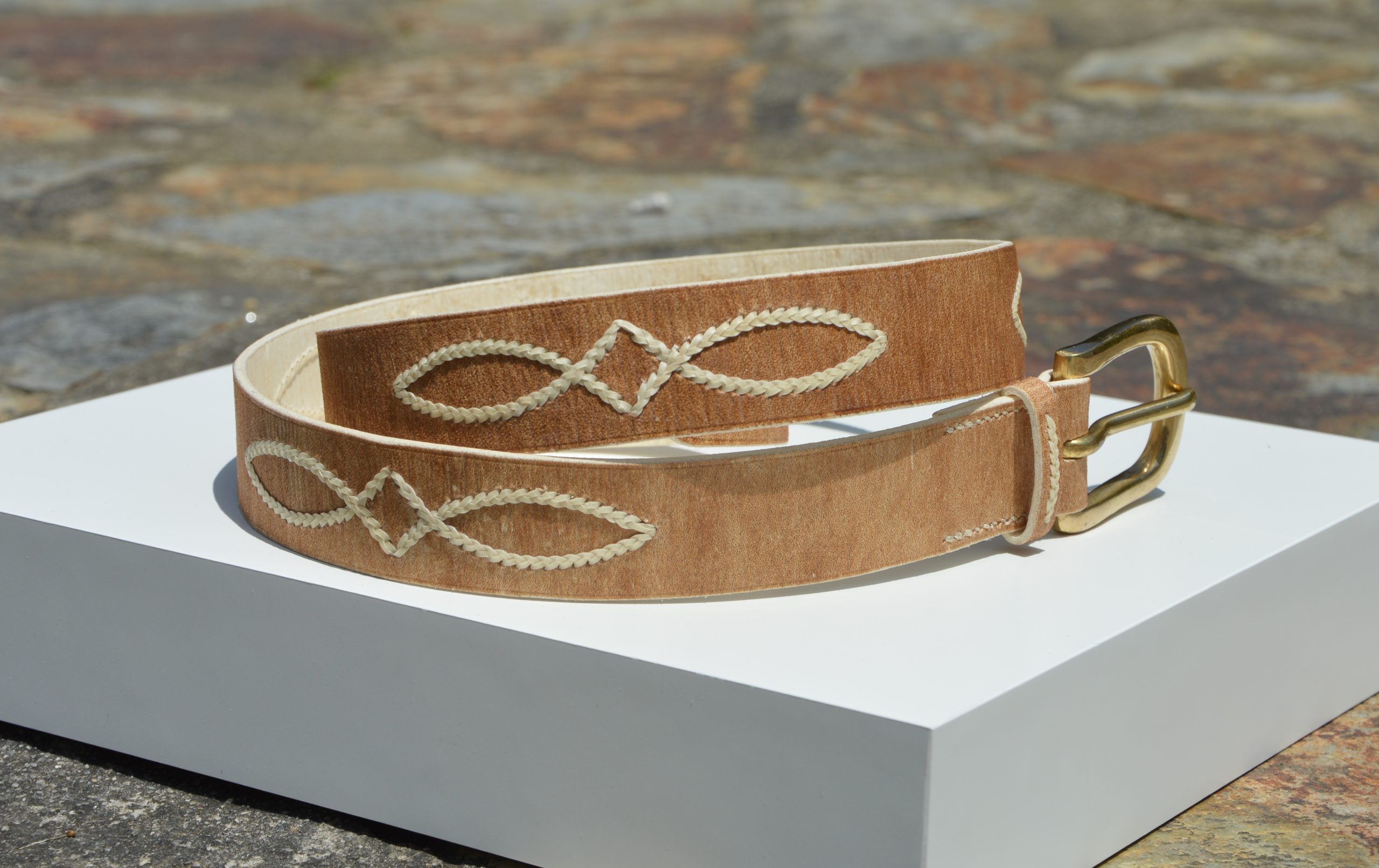 "Cinturón de Cuero Ojo de Perdiz disponible por €150.00. Elaborado con las técnicas y materiales típicos de la artesanía criolla, este cinturón presenta cuero crudo con costuras decorativas de tiento y una hebilla de latón macizo. Puedes consultarnos por más opciones de diseño. Disponible en 30 mm o 35 mm de ancho."