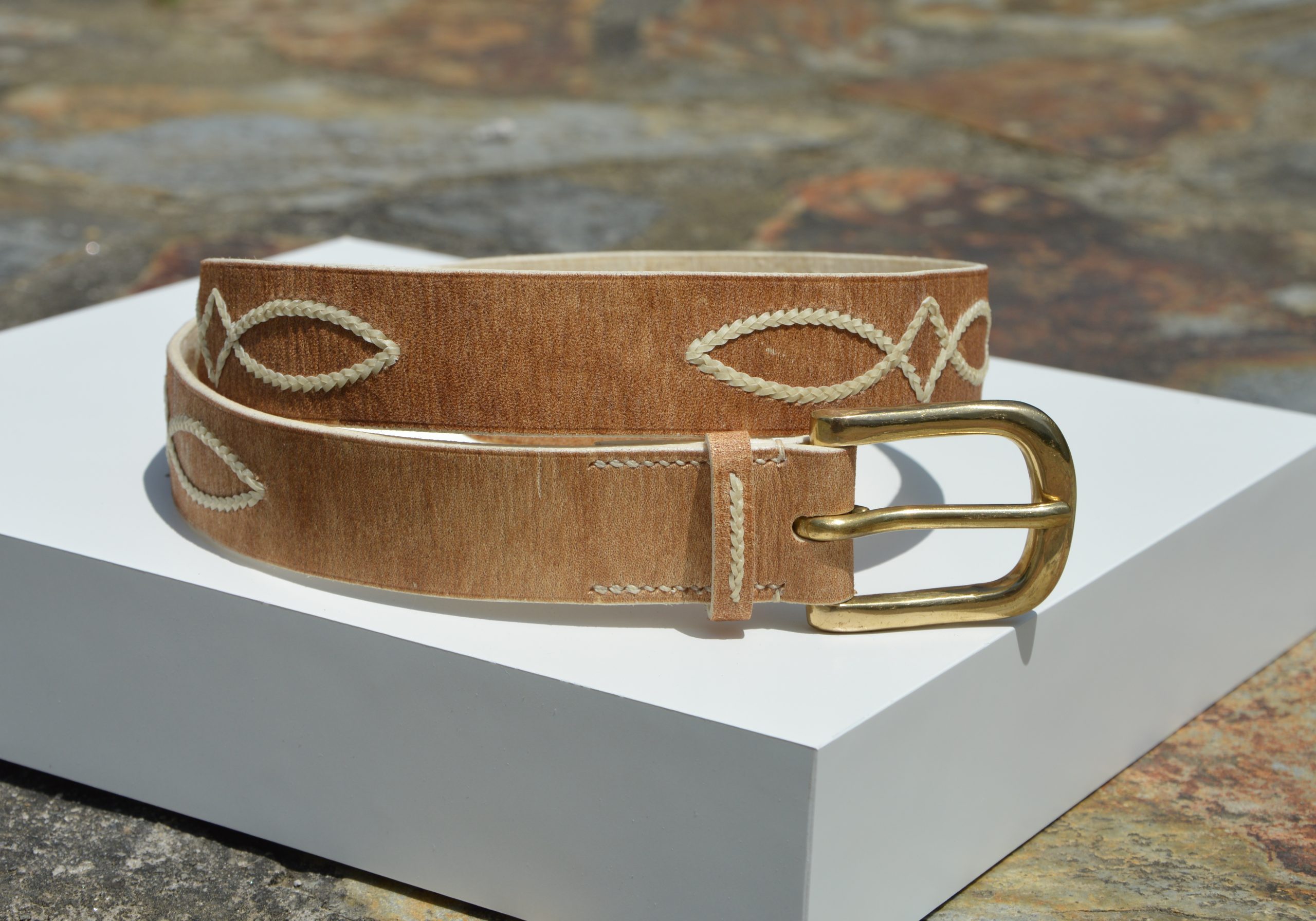 "Cinturón de Cuero Ojo de Perdiz disponible por €150.00. Elaborado con las técnicas y materiales típicos de la artesanía criolla, este cinturón presenta cuero crudo con costuras decorativas de tiento y una hebilla de latón macizo. Puedes consultarnos por más opciones de diseño. Disponible en 30 mm o 35 mm de ancho."