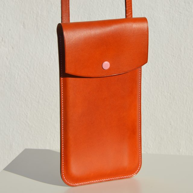 Estuche de viaje Phone/Travel Case, disponible por €120.00. Ideal para llevar el móvil o el pasaporte, elaborado en piel de curtido vegetal con detalles de color. Cosido a mano al 100% con hilos de lino."