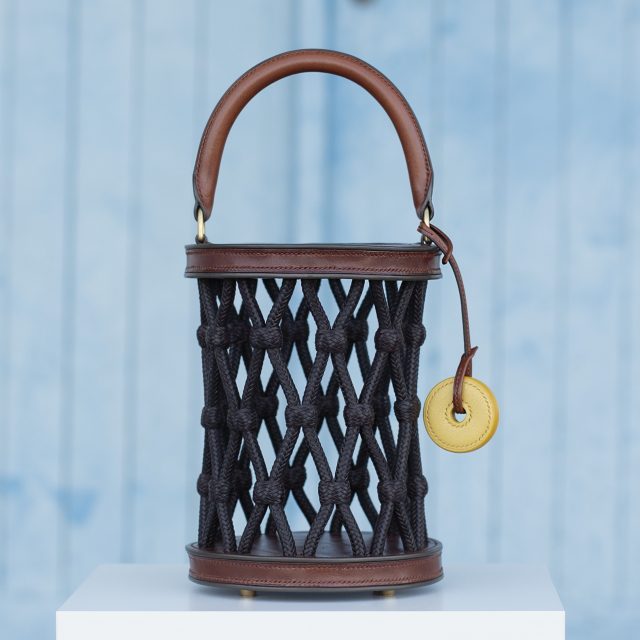 "Bolso Nasa, pieza única y finalista en los premios Artesanía de Galicia 2023. Elaborado con piel de curtido vegetal y herrajes de latón macizo, trenzado y ensamblado a mano. Cosido con hilos de lino y dimensiones de 34×16 cm. Categoría: Bolsos. Una obra artesanal de alta calidad en homenaje a la cultura marítima de Galicia."