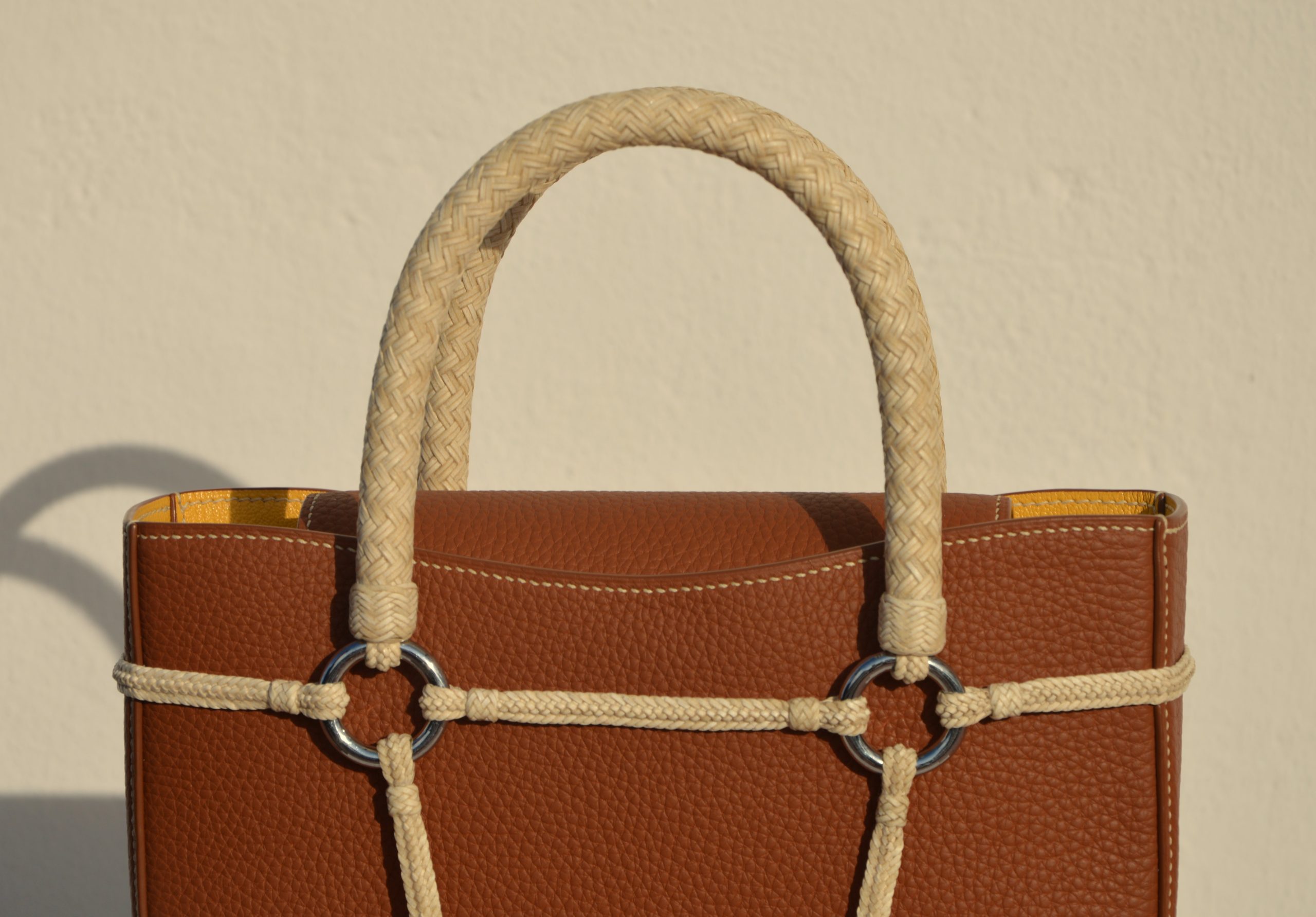 "Bolso Tobiano de edición limitada, elaborado en piel Taurillon Lagun con asas tejidas a lezna y arnés trenzado en cuero crudo. Forrado en piel de cabra francesa y cosido a mano con hilos de lino. Dimensiones: 6cm x 25cm x 30cm, incluyendo asas."