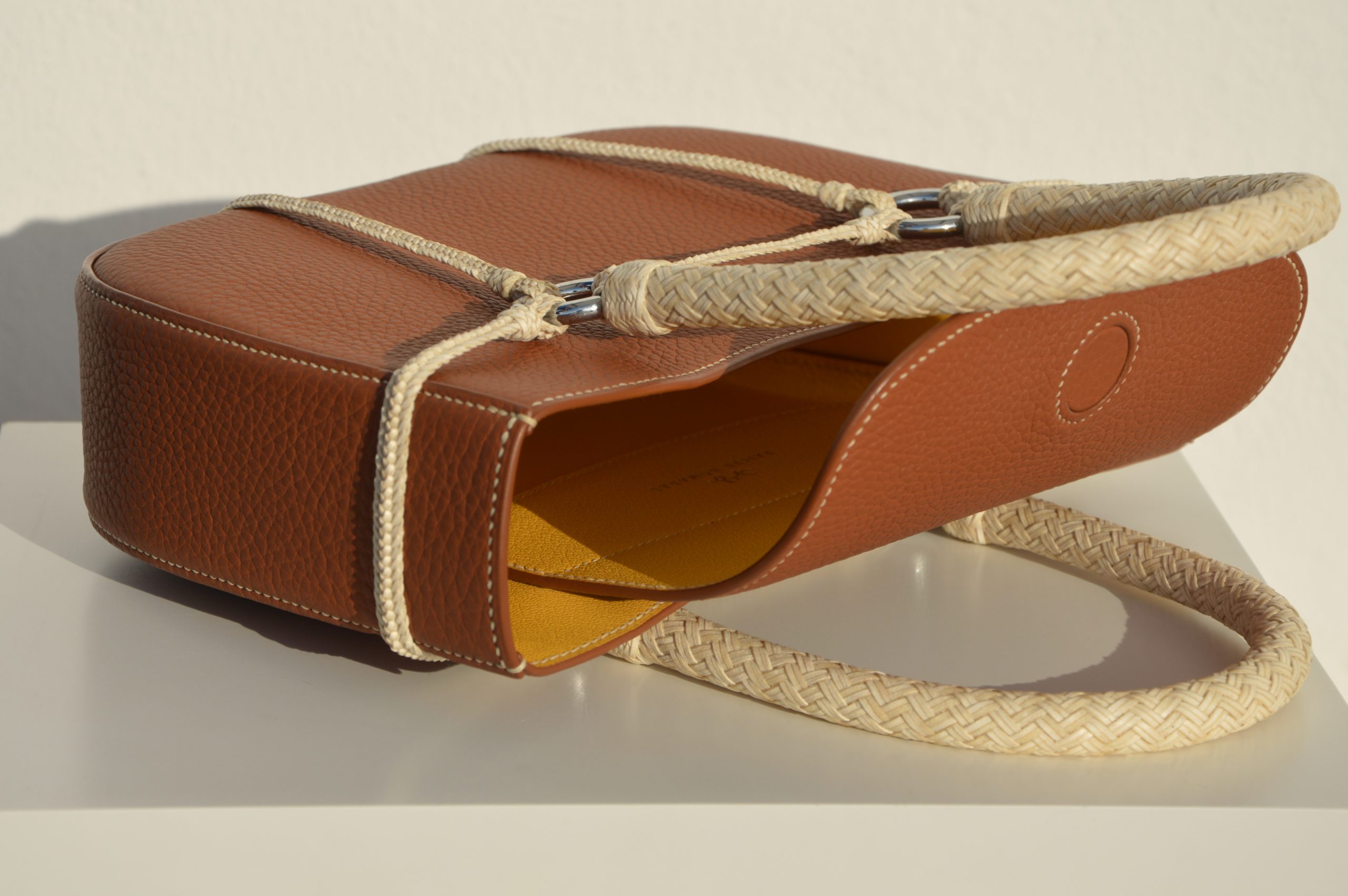 "Bolso Tobiano de edición limitada, elaborado en piel Taurillon Lagun con asas tejidas a lezna y arnés trenzado en cuero crudo. Forrado en piel de cabra francesa y cosido a mano con hilos de lino. Dimensiones: 6cm x 25cm x 30cm, incluyendo asas."